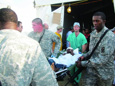 Perlyn and U.S. military officers transport a patient from a hospital tent.