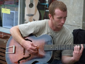 A street musician, or busker,  plays the acoustic guitar in the Delmar Loop. (Eve Root)