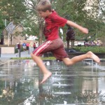 A young boy skips through a fountain play area at the ne City Garden. (Seth Lewis)