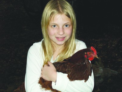 Leah Peipert stands outside her Clayton home with Rhody, a Rhode Island Red chicken. The family spends about five to ten minutes each day caring for the chickens.