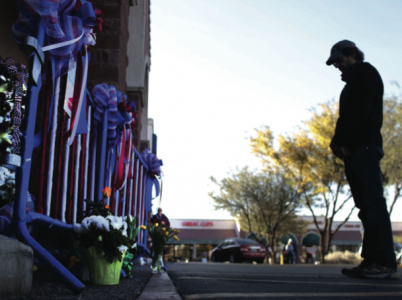 A shopper spends a moment at a makeshift memorial in front of the Safeway store after it opened on Saturday, January 15, 2011, for the first time since a shooting seven days ago that killed six and wounded 13, including Rep. Gabrielle Giffords. (Gina Ferazzi/Los Angeles Times/MCT)
