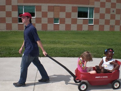 An Education Exchange Corps Volunteer pulls students on a wagon during a class break. (Courtesy of Elad Gross)