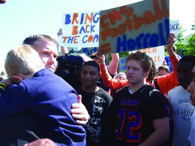 Coach Horrell Horrell holds his son as he meets with students in the circle on May 6, when hundreds of students walked out of class to protested his dismissal as football coach by walking out of class. (Thalia Sass)