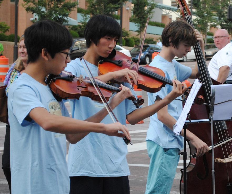 Lawrence Hu, Matthew DelaPaz, and Benjamin Schneider playing their instruments at the Art Fair.