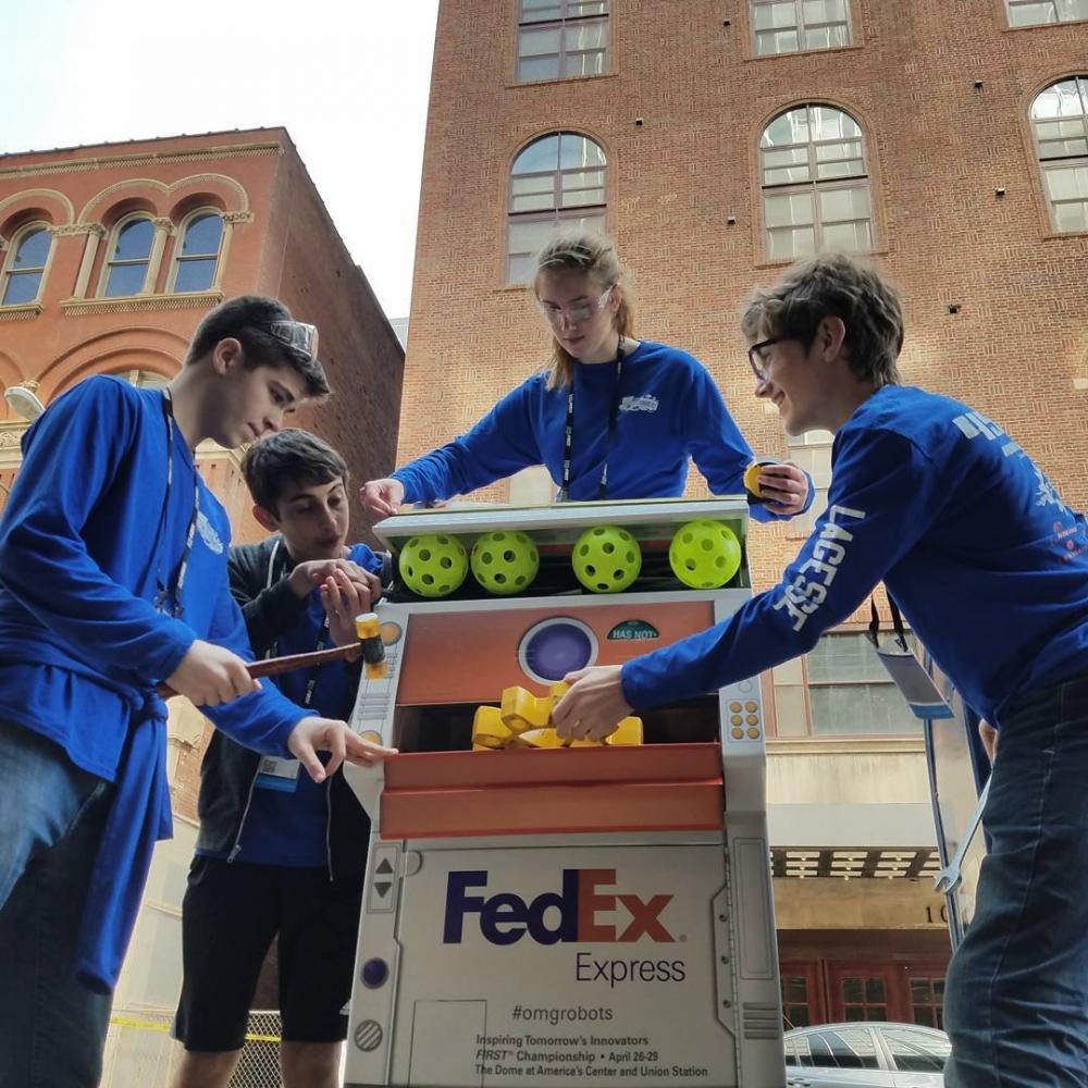 Robohounds pose with a robot-themed drop box for the Fedex Innovation Challenge. From left to right: Zachary Sorensen, Justin Guilak, Echo Gaugush, Jacob LaGesse.