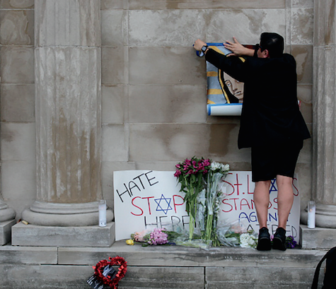 A woman promotes peace by hanging a sign. 