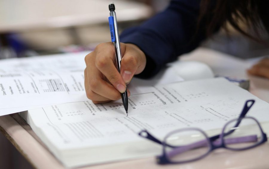 A student works a problem in the pages of a test prep book during an 18-hour practice class at Neuqua Valley High School on July 21, 2015.