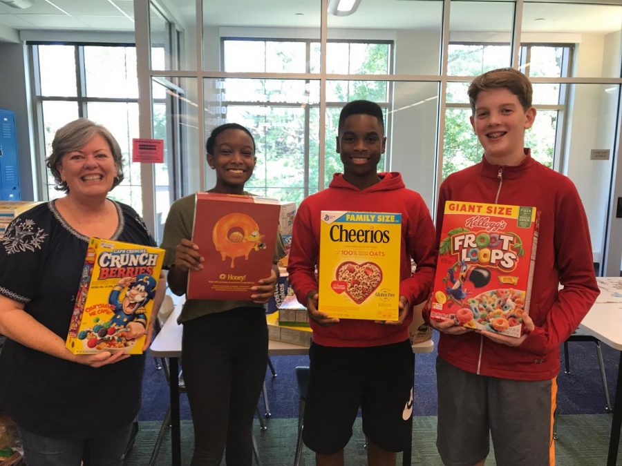 Michelle Schiller-Baker (left) and students hold boxes of cereal. They were helping provide breakfast for St. Marthas Hall.