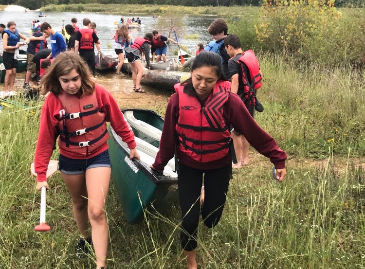 Counselor, Kim Cheng and CIT, Claudia Taylor carry their canoe out of the watrer.