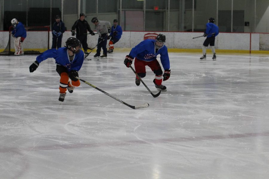 Two Clayton ice hockey players race against each other across the ice during one of the team's practices.