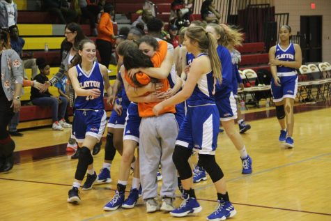 Juniors Sammy Williams (left) and Sara Litteken share a celebratory hug as the rest of their teammates run up to join in, after beating Jennings 38-26 in the Class 4 District 6 Championship Finals. 