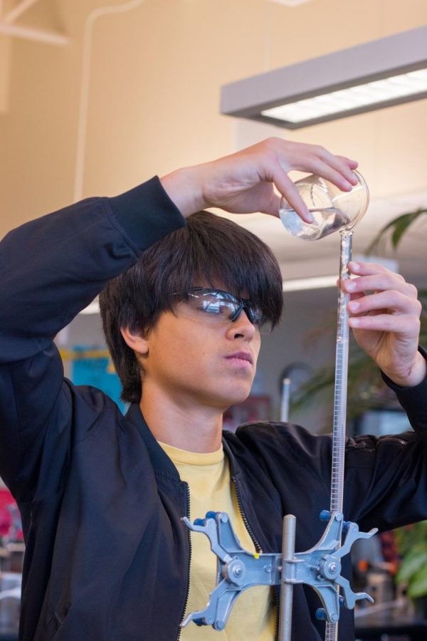 Junior Emilio Rosas-Linhard pours a solution into a graduated cylinder during a chemistry class. Even though the official measurement system is imperial, American scientists almost exclusively teach and use the metric system.