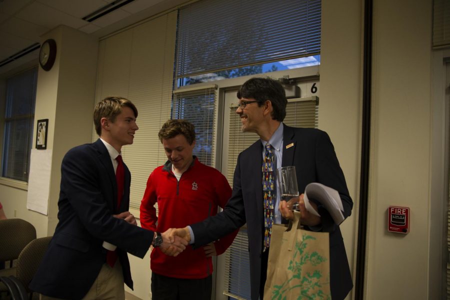 Greg Pierson shakes hands with new board president Joe Miller after a successful 6-1 vote to approve the Student Representation on the Board of Education.