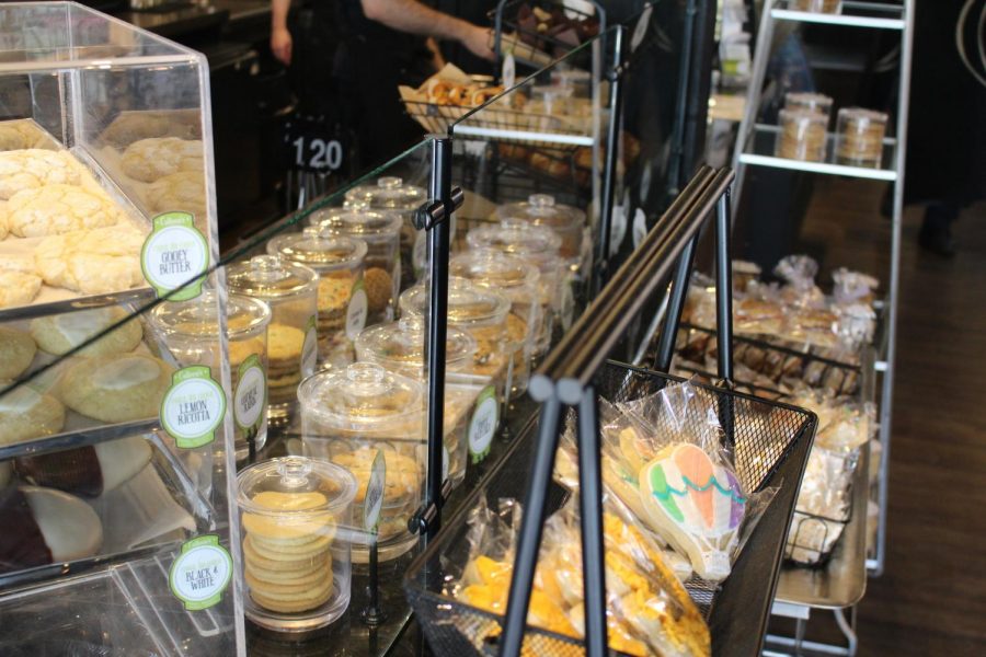 Cookies, macarons and muffins glisten in the light within the bakery display case at Colleens.