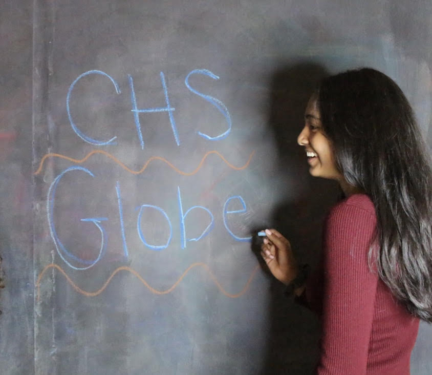 Dheera Rathikindi writing on a chalk board at the St. Louis Selfie Room. 