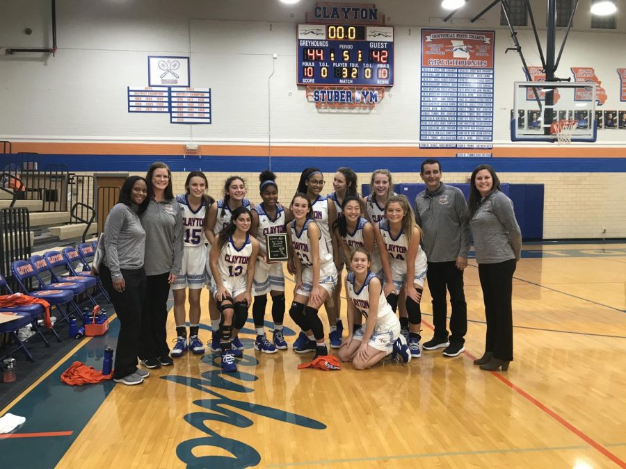 The Girls Varsity Basketball team poses for a photo with their victory plaque. 