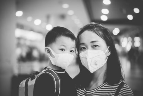 An Asian mother and a kid wearing masks in the picture.