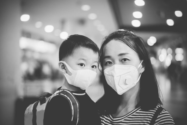An Asian mother and a kid wearing masks in the picture. 