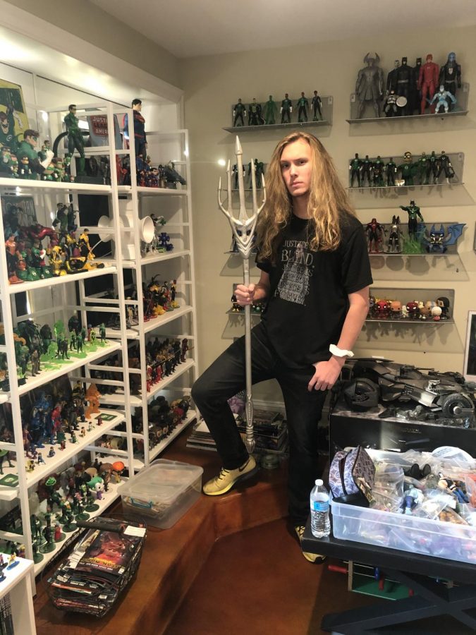 Keilan Morrissey posing beside his comic collection. Morrissey has collected thousands of comics,  action figures and other memorabilia.