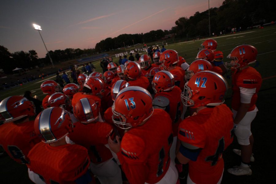 Football players huddle before a game at Clayton High School