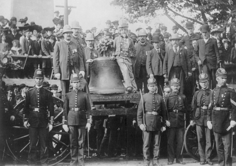 UNITED STATES - CIRCA 1903:  Liberty Bell on a wagon surrounded by men in uniform and others; man dressed as Uncle Sam leaning on the bell.