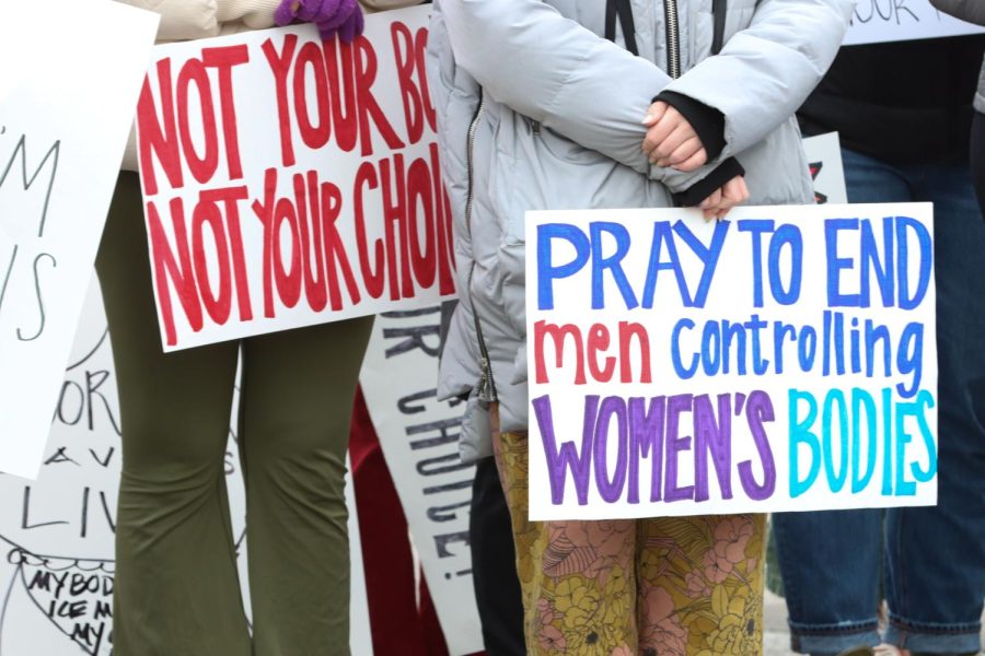 Attendees at the rally hold signs saying, Pray to end men controlling womens bodies and Not your body. Not your choice. 