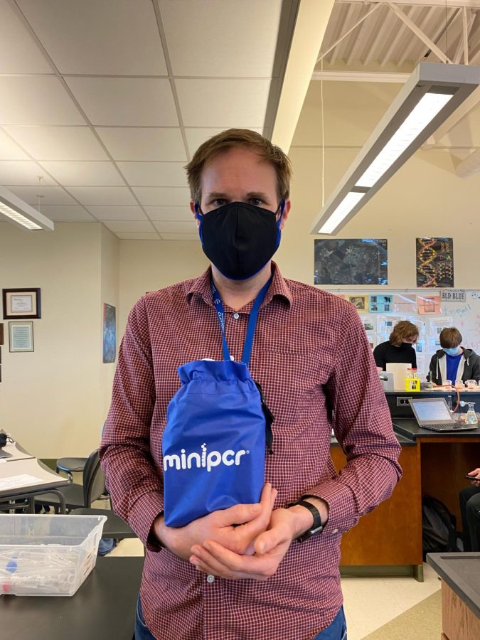 Adam Bergeron holds up one of the school’s PCR machines that he hopes will be incorporated into the science curriculum at the high school. 