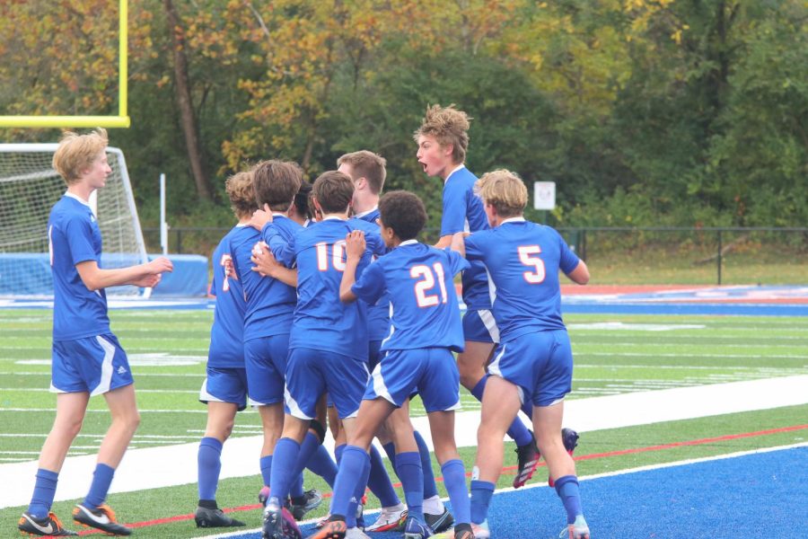 The boys soccer team celebrates on the field. 