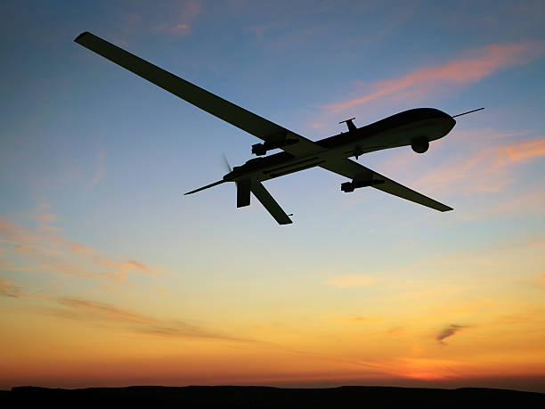 A drone is silhouetted against a sunset.