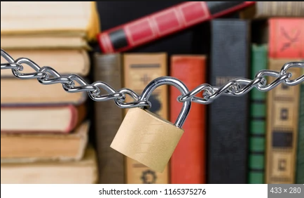 A padlock on a chain restricts access to a bookshelf full of books.