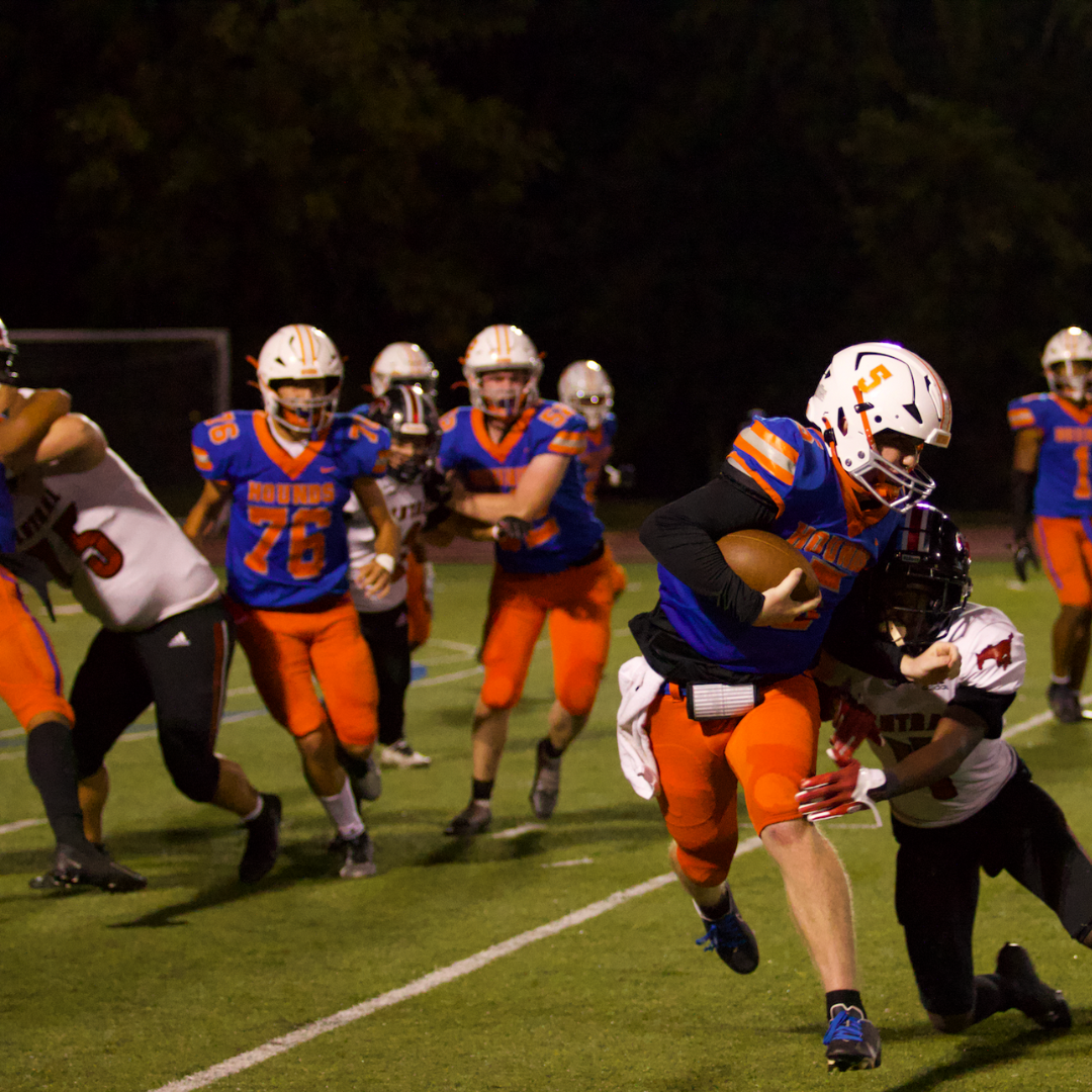 Clayton-Brentwood player runs towards the end zone as he attempts to avoid a tackle
