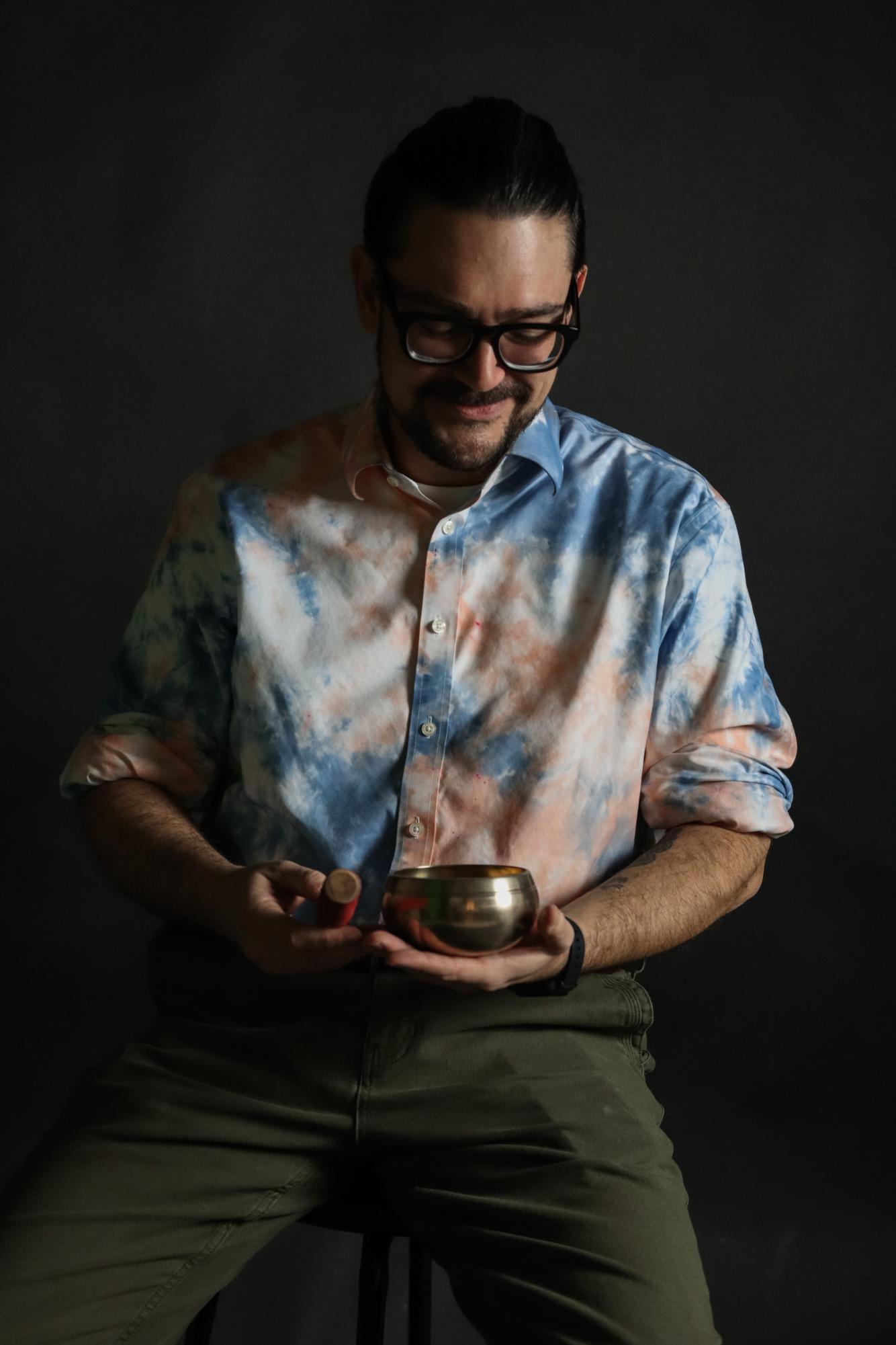 Social Studies teacher Daniel Glossenger looks down at a Tibetan singing bowl that he keeps in his classroom. 