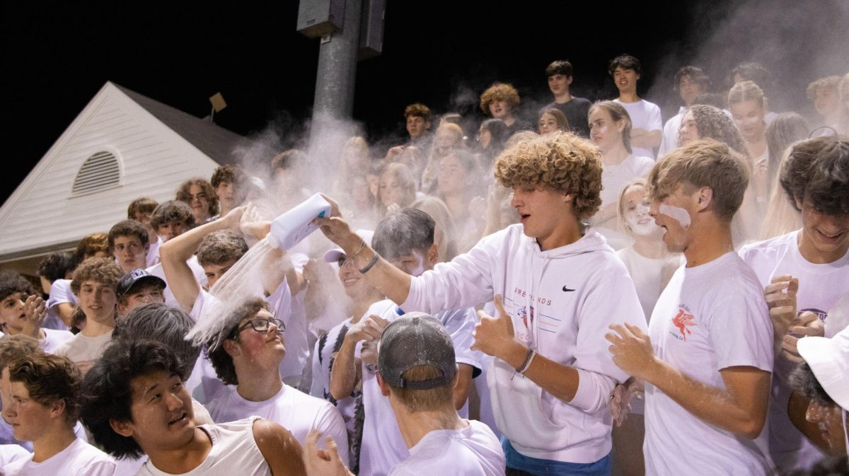 Students throw baby powder on each other for “white-out night” at a football game. 