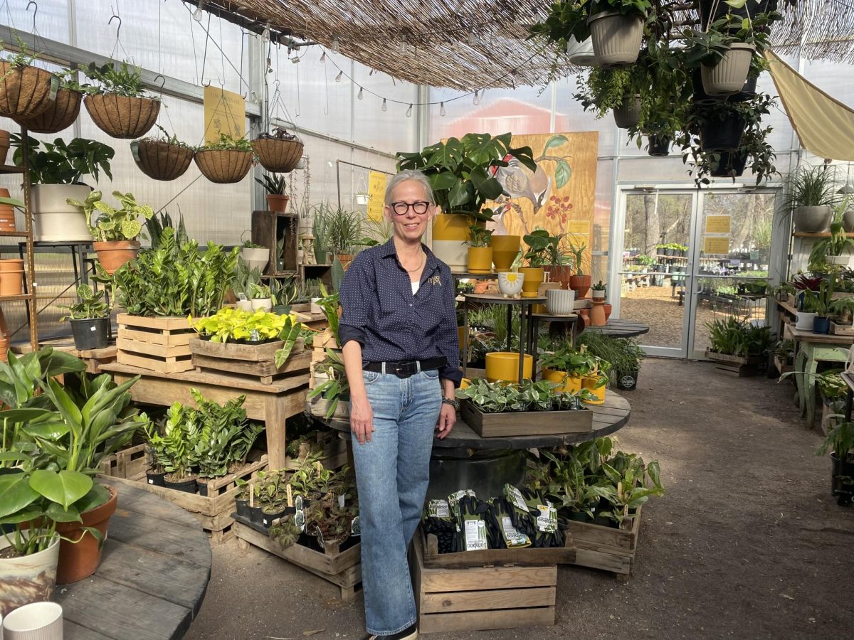 Owner Tammy Behm stands amidst crates overflowing with verdant foliage within the greenhouse.