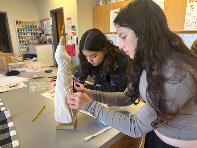 Sophomore Olivia Fine drapes fabric on a mannequin in Intro to Fashion and Interior Design.