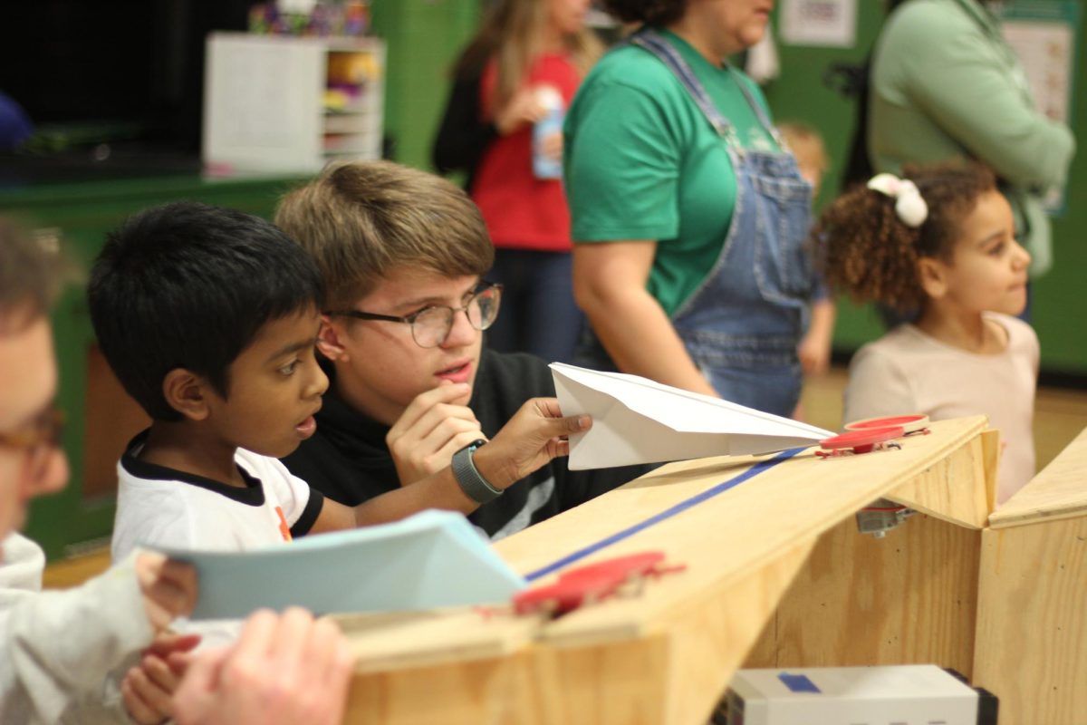 Senior Lucas Boeyink helps Glenridge students make crafted paper airplanes fly using the airplane launcher. The Robohounds built the launcher with their materials in the school’s engineering and design room. “Seeing the excited looks on the kids' faces made trial and error run before the event worth it,” Boeyink said.