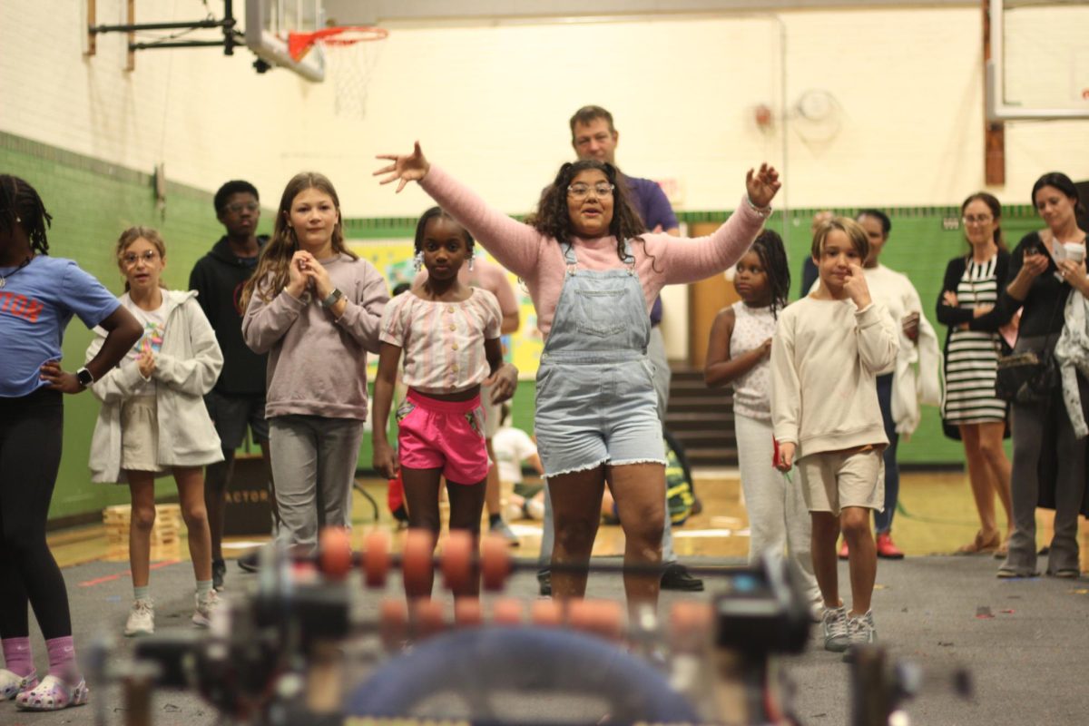 Elementary students wait for Dumpling to launch a ring into the air. [The activity] turned into a game of catch between the robot and the kids. “I think we all felt a sense of fulfillment by being a part of an event that inspired kids,” Poovathumkadavil said.