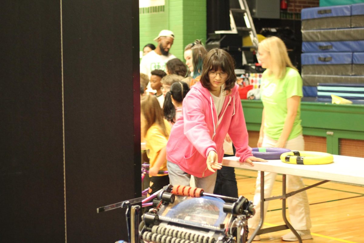 Sophomore Isadora Dolan places a ring into Dumpling. Dumpling was the team's chosen name for last season’s robot. “Sometimes kids stand by the table next to me to see the ring go into Dumpling. I liked seeing how excited the kids were about interacting with the robot. It was really sweet seeing how much fun they were having, and it felt great to help out with that,” Dolan said. 