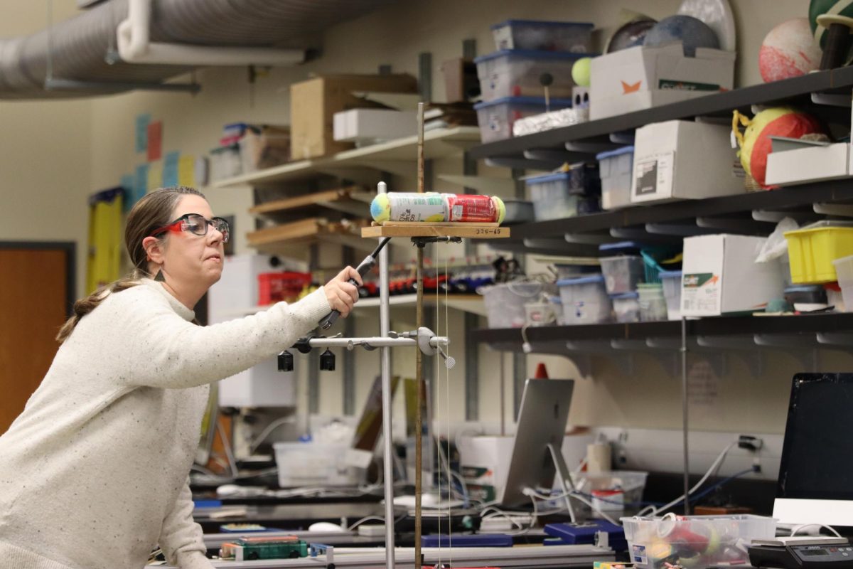 AP Physics teacher Jennifer Adams lights a firecracker placed between two cans. Students were given the mass of one of the cans and the distance the cans traveled and had to find the unknown mass of the other can.