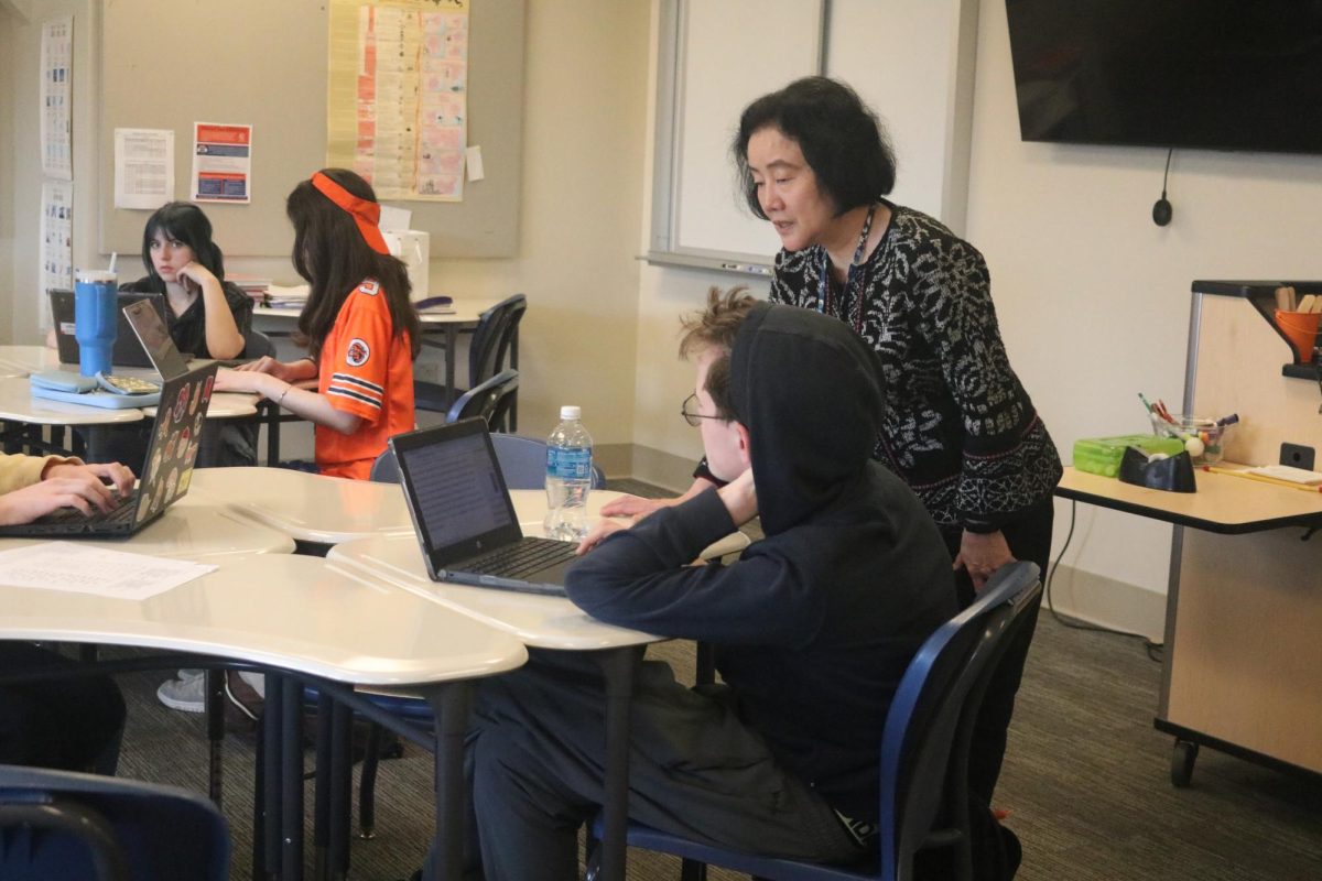 Zhang helps a student in her class.