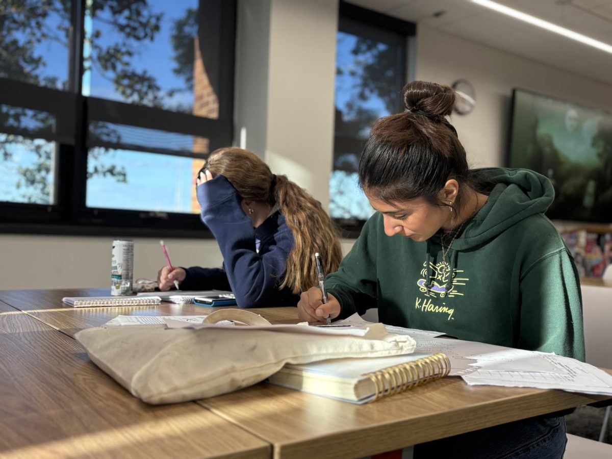 Junior Harper Drake and senior Gasya Berberian diligently work on homework, both are against the phone ban and believe having their phones would help them effectively complete their work. 