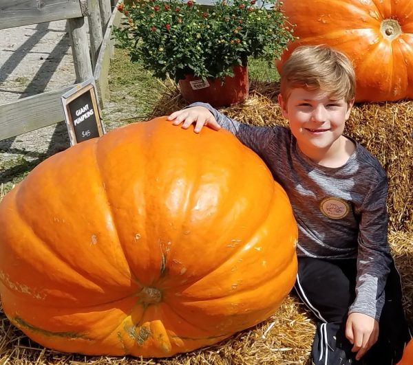 Elementary schooler Nate Linnenbringer poses with a giant pumpkin at Eckerts on a school field trip in 2018.