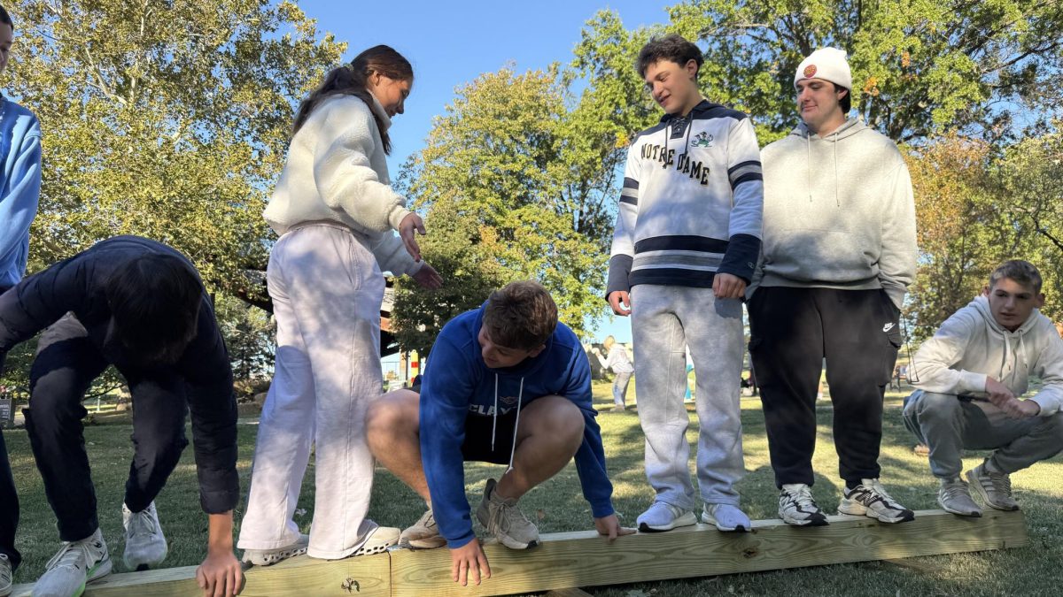 Tucker Abeles crouches to allow teammate space to climb over. Him and his group pooled their brainpower to figure out how to switch sides on a balance beam.