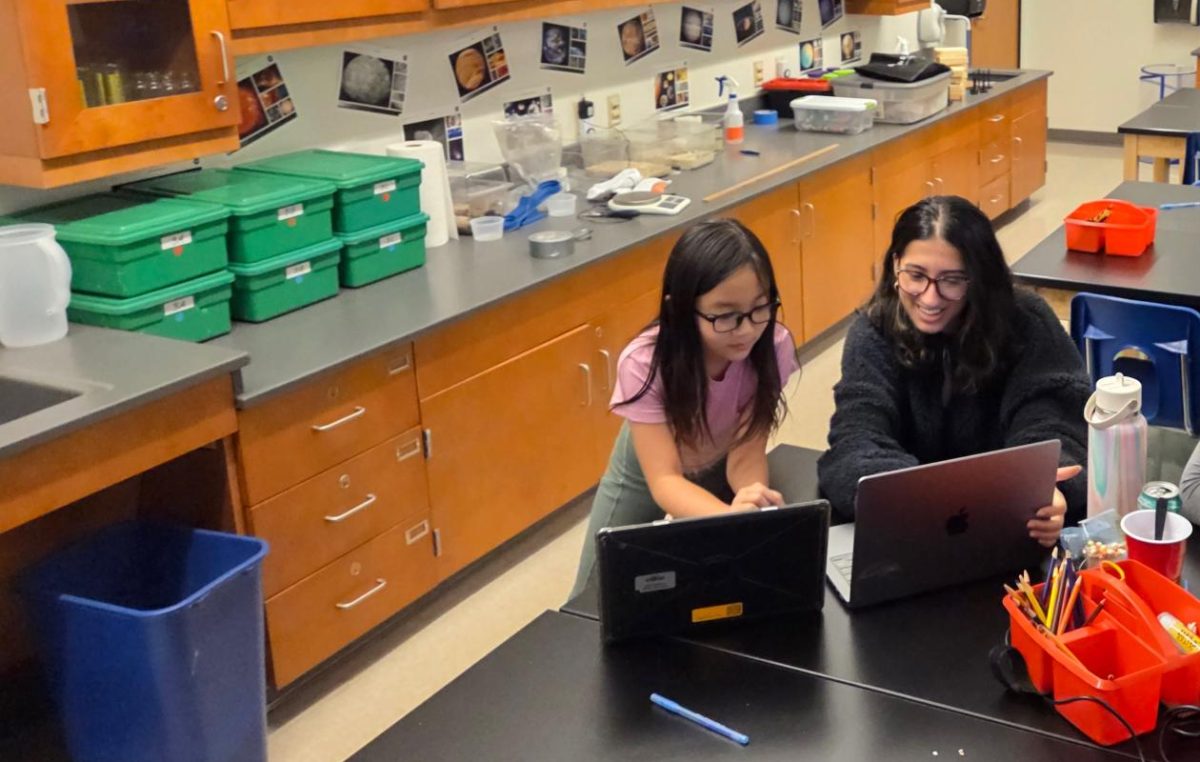 Junior Addy Poudel sits and works with Meramec elementary fourth grader Evelyn Ching on her science fair project. Ching took different forms of slime and tested its absorption and spreadability.